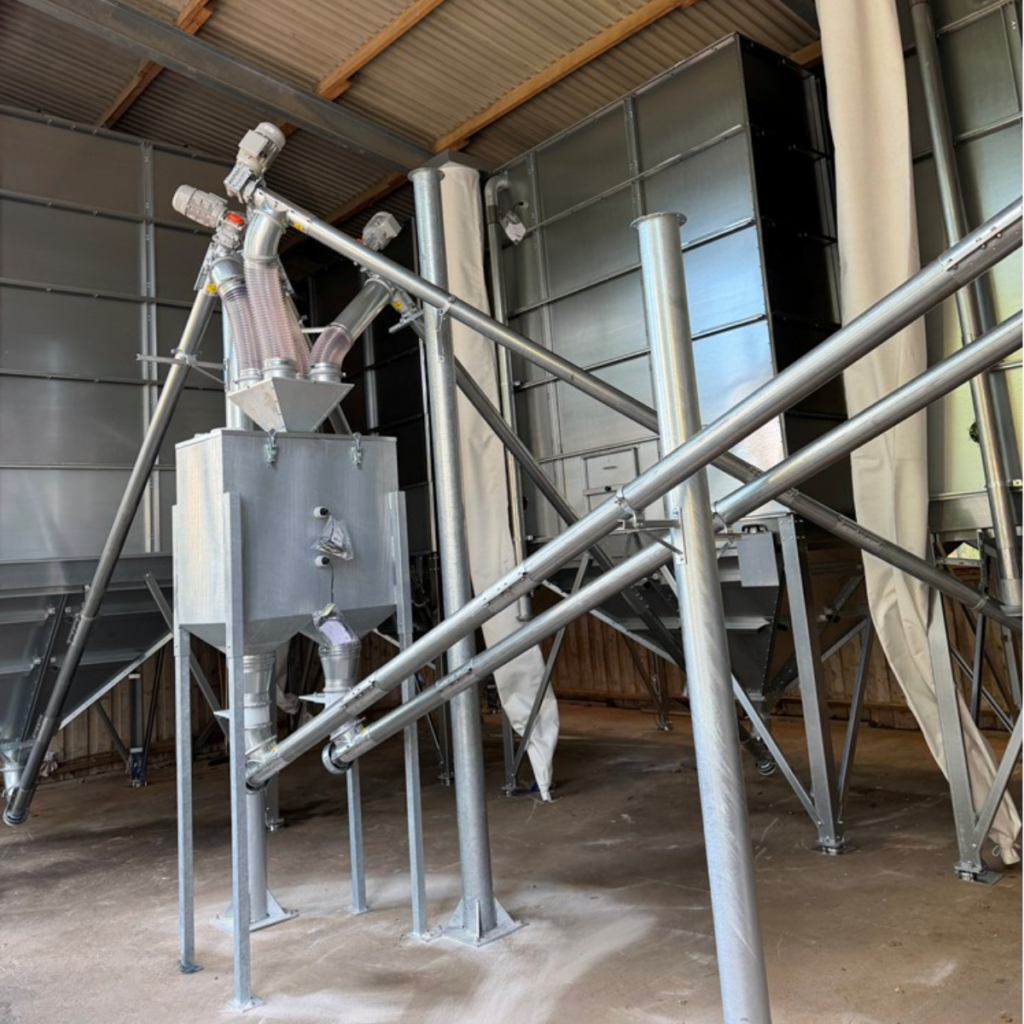 Metallsilo och transportskruvar för spannmål i ett kompakt förvaringsutrymme.
