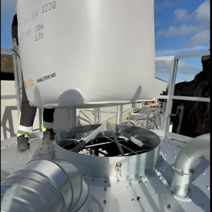 En stor vit Topplucka med knivkors för toppanslutning på en industriell silosäck hänger ovanför en metalltratt på en plattform bredvid en silo. Rör, bultar och benen på en person i skyddsutrustning syns nära Topplucka, allt mot en bakgrund av blå himmel med spridda moln.
